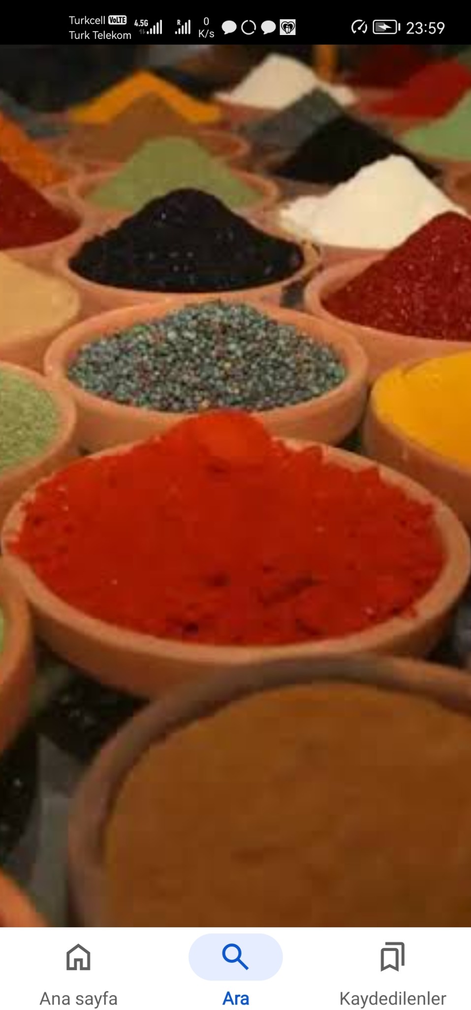 Grup glinianych miseczek wypełnionych różnokolorowymi przyprawami, ułożonych w rzędach i kolumnach, tworzących barwną mozaikę smaków.