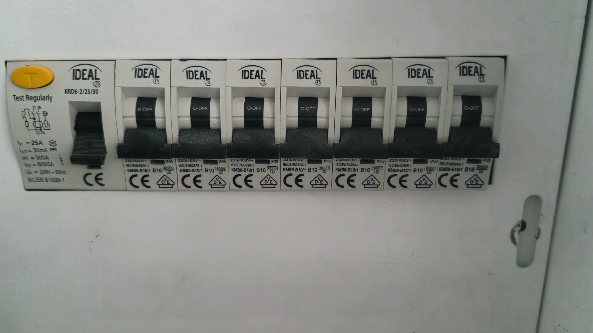 Rozdzielnica elektryczna z wyłącznikami nadprądowymi marki Ideal, widoczne oznaczenia i parametry techniczne. Jeden wyłącznik w pozycji ON, reszta OFF.