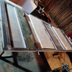 SPAW-BUD - Konstrukcja metalowa z wypełnieniami z płyt, prawdopodobnie w trakcie tworzenia ścianki działowej lub elementu wykończenia wnętrz. Widoczny pracownik w tle.