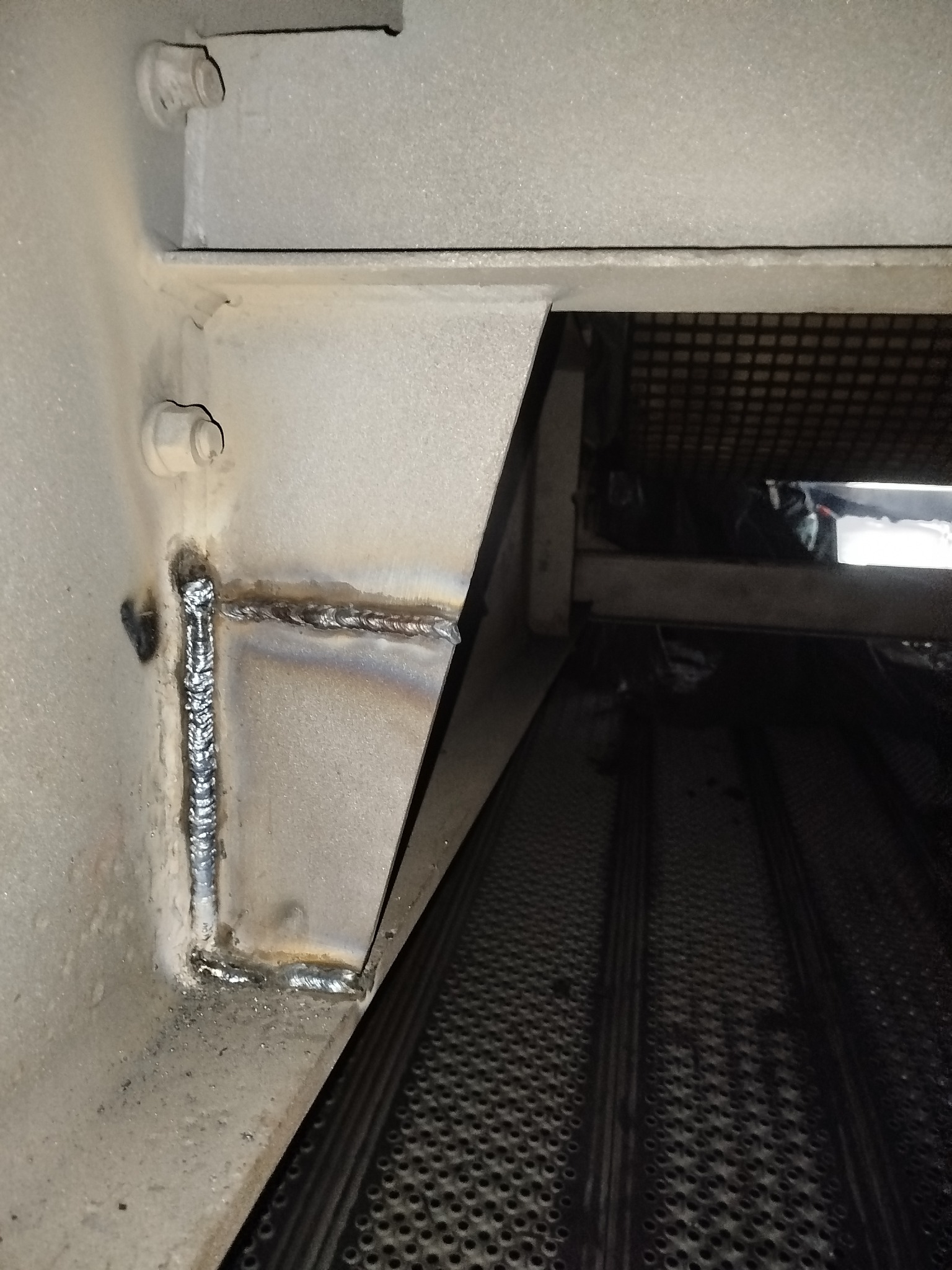 Spoina spawalnicza łącząca metalowe elementy konstrukcyjne, widoczne ślady obróbki i drobne niedoskonałości. Ujęcie z bliska, ukazujące detale złącza.