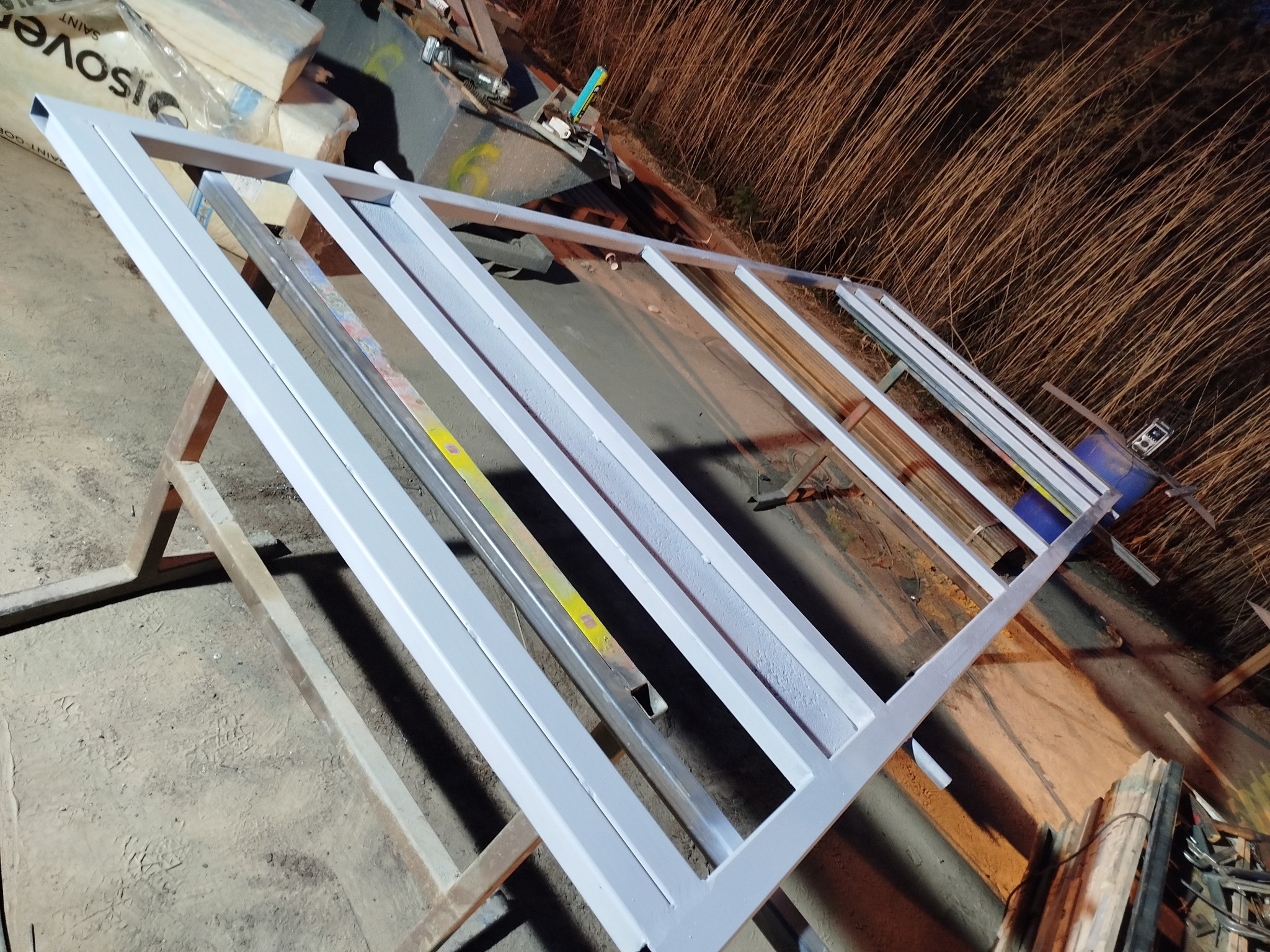 Malowana na szaro metalowa konstrukcja w warsztacie w Jedwabnie, widoczna z góry. Elementy konstrukcyjne i narzędzia w tle. Przygotowanie do montażu?