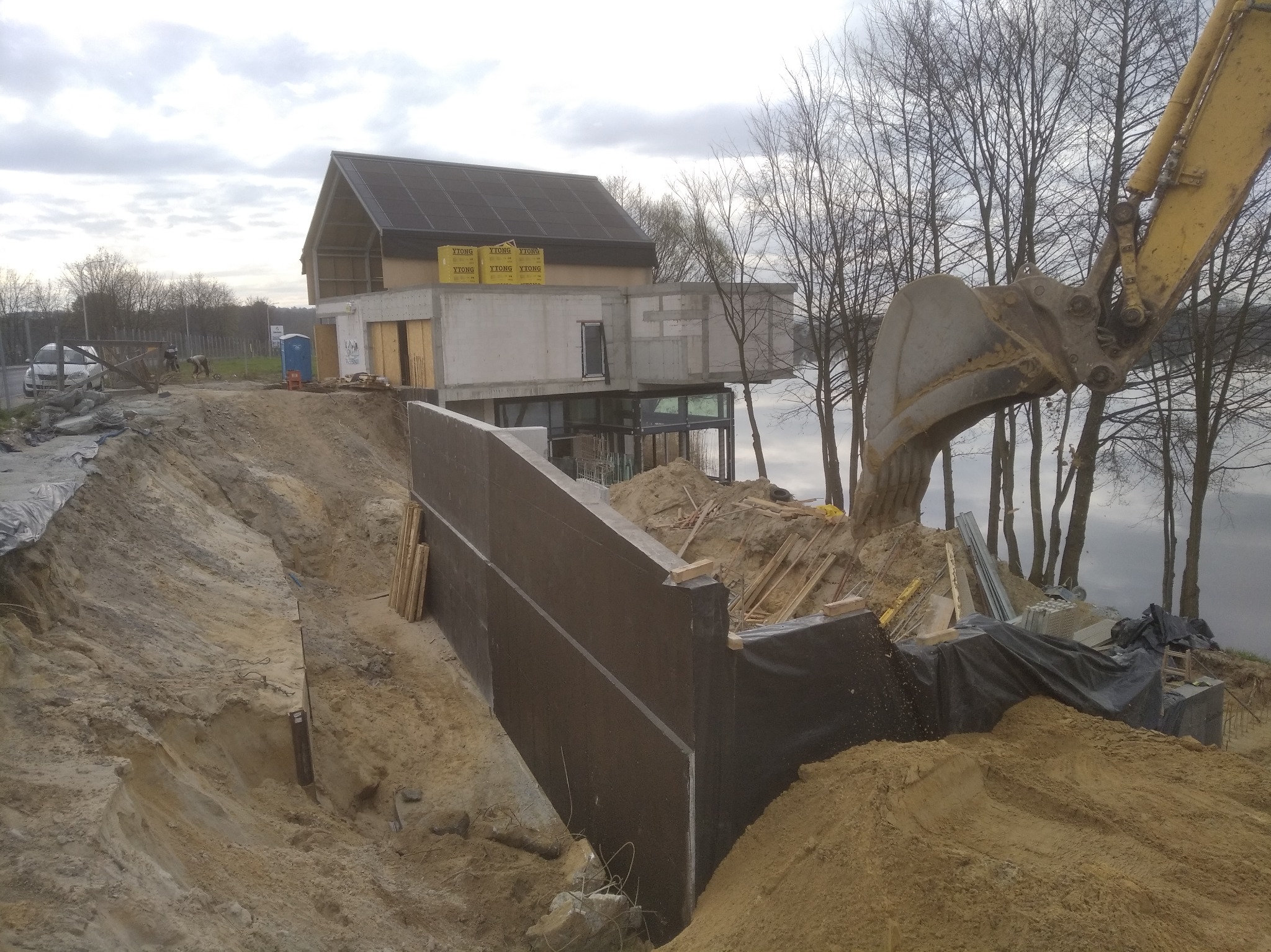 Budowa domu z widokiem na jezioro: fundamenty, ściany z betonu komórkowego Ytong, koparka w akcji. Etap prac ziemnych i wznoszenia konstrukcji.