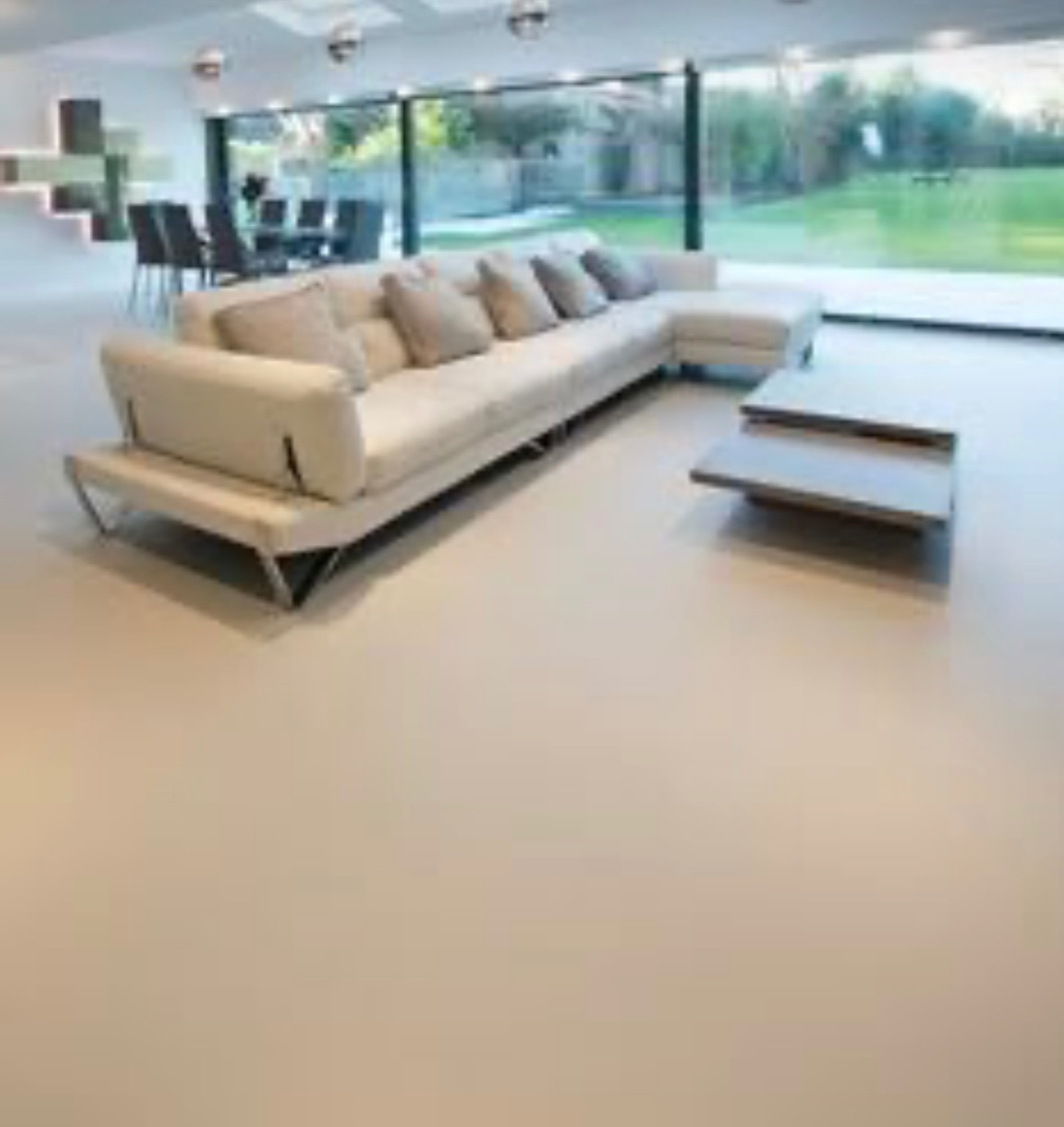 Jasna, bezspoinowa podłoga w nowoczesnym salonie z dużym oknem na ogród. Minimalistyczny design z sofą i stolikiem kawowym. Gładka powierzchnia.