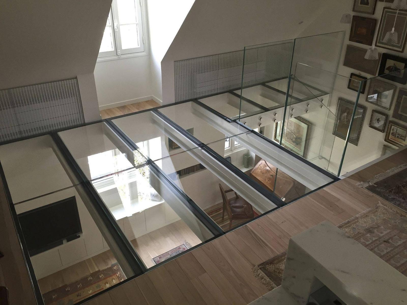 Szklana podłoga w nowoczesnym domu, widok z góry. Przezroczyste panele oddzielają pokoje, tworząc unikalne połączenie przestrzeni. Widoczne elementy wystroju wnętrz.