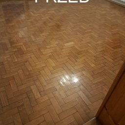 PRO-PODŁOGI - układanie , renowacja - Parkiet dębowy ułożony w jodełkę przed renowacją, widoczne ślady użytkowania i zarysowania. Ujęcie z góry, fragment ściany i drzwi w tle. Napis PRZED na zdjęciu.