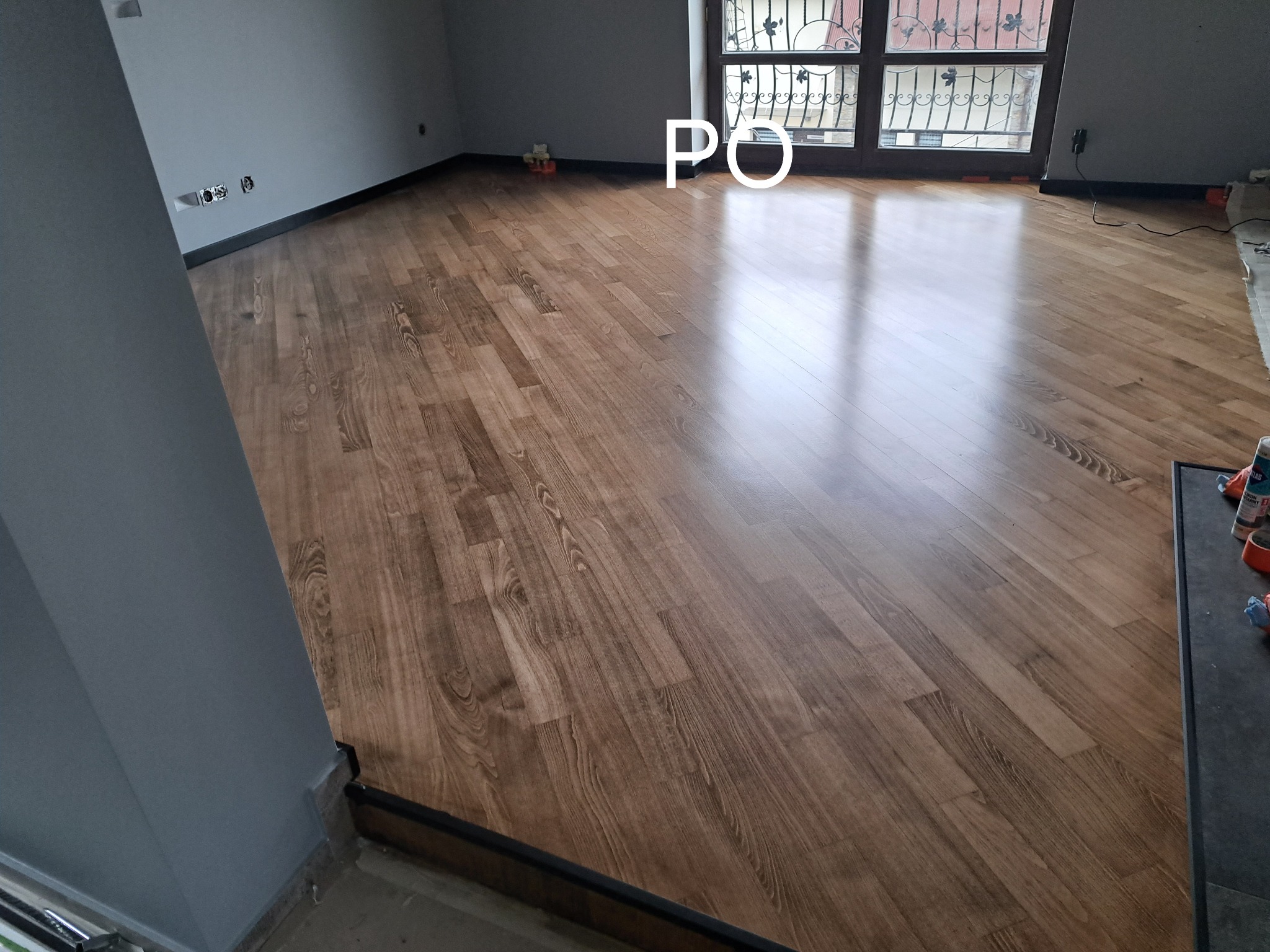 Ułożone panele podłogowe w odcieniach brązu, widok z perspektywy podłogi w pomieszczeniu w Niedźwiedziu. Widoczne listwy przypodłogowe.