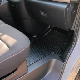 Mateusz Jachowski - Wnętrze samochodu z szarą tapicerką foteli i czarną gumową wycieraczką na podłodze. Widoczne detale deski rozdzielczej i otwarte drzwi.