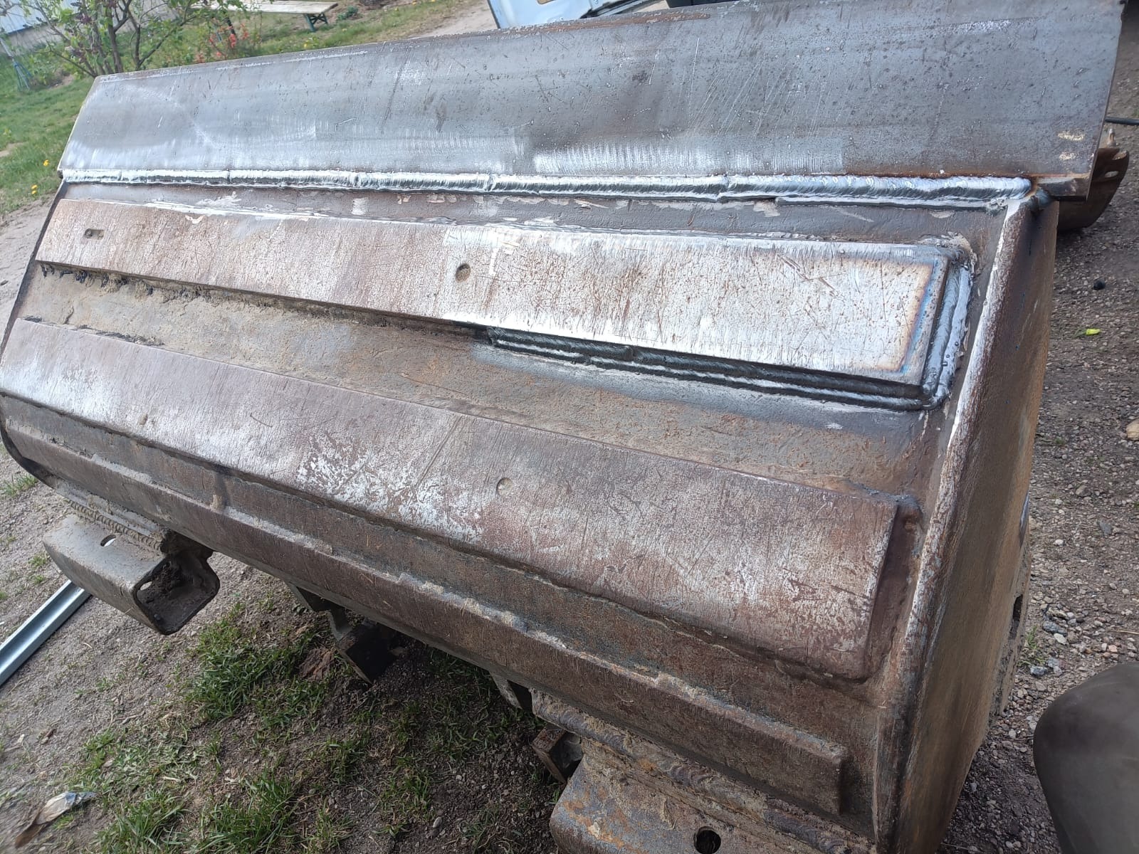 Wzmocniona spawami łyżka skarpowa koparki, z widocznymi śladami napraw i świeżymi spawami. Detaliczne ujęcie metalowej konstrukcji po renowacji.