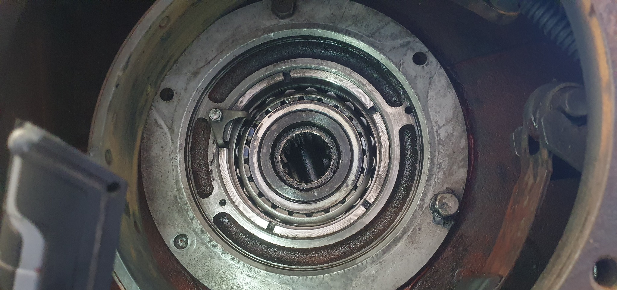 Wnętrze piasty koła z widocznymi łożyskami i elementami mocującymi. Detal mechanizmu z bliska, ukazujący zużycie i smar.