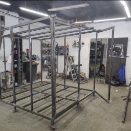 TECH-WELD - Stalowa konstrukcja szkieletowa w hali warsztatowej, spawana z profili kwadratowych, z widocznymi śladami spawania i narzędziami w tle. Etap budowy.