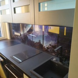 CORKY - Nowoczesna kuchnia z szafkami w odcieniach szarości i oryginalnym panelem szklanym z motywem kosmicznym. Czarny zlew i płyta indukcyjna wkomponowane w blat.