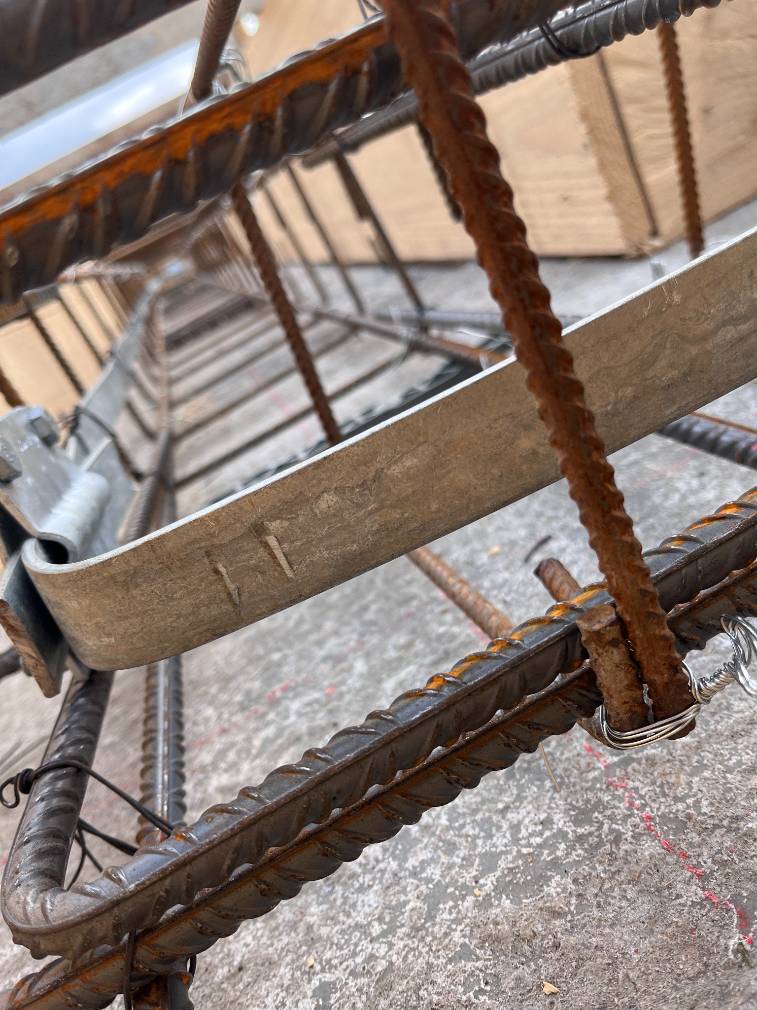 Zbrojenie fundamentów z bliska, widok z dołu w Jordanowie. Konstrukcja z prętów żebrowanych, połączonych drutem i metalowymi elementami.