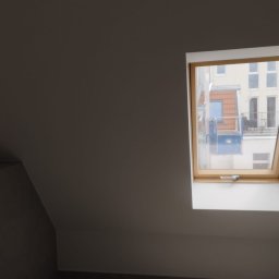 Krystian Barczyński - Szare poddasze z oknem dachowym i widokiem na budynek z rusztowaniem. Świeżo pomalowane ściany. Minimalistyczny styl.