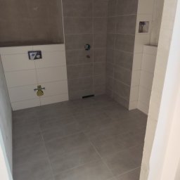 KJP Wykończenia wnętrz Tomasz Pietras - Wykończona łazienka w szarościach z częściowo położonymi białymi płytkami. Widoczne instalacje pod umywalkę i baterię. Minimalistyczny design.