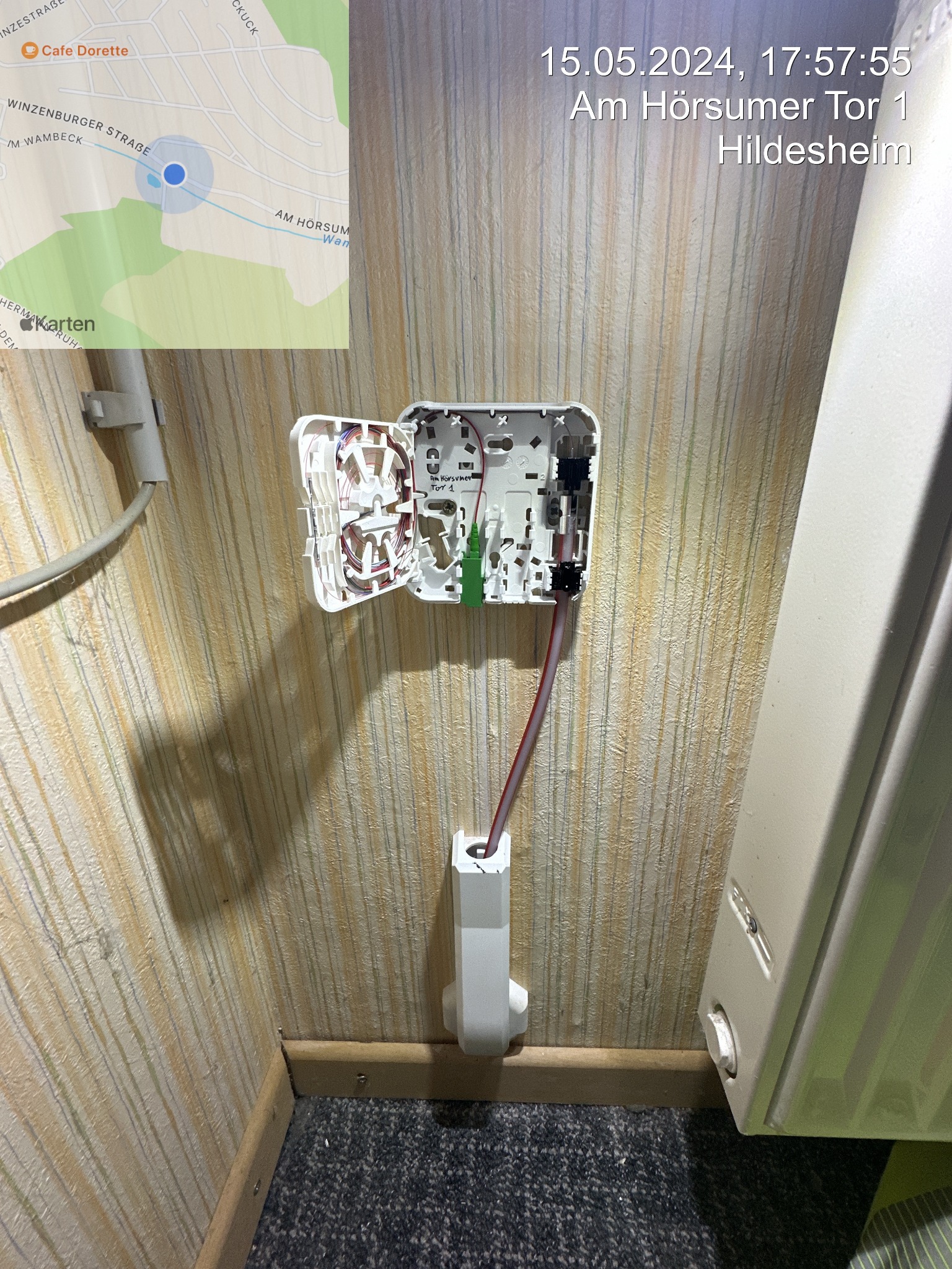 Otwarta puszka instalacyjna światłowodowa na ścianie w Sokolnikach. Widoczne kable i złącza. Obok grzejnik. Na górze kadru mapa z zaznaczoną lokalizacją.