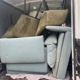 FlexiGo4U Karolina Ciołek - Wnętrze białego busa wypełnione meblami tapicerowanymi w odcieniach zieleni i błękitu, zabezpieczonymi kocem, gotowymi do transportu.