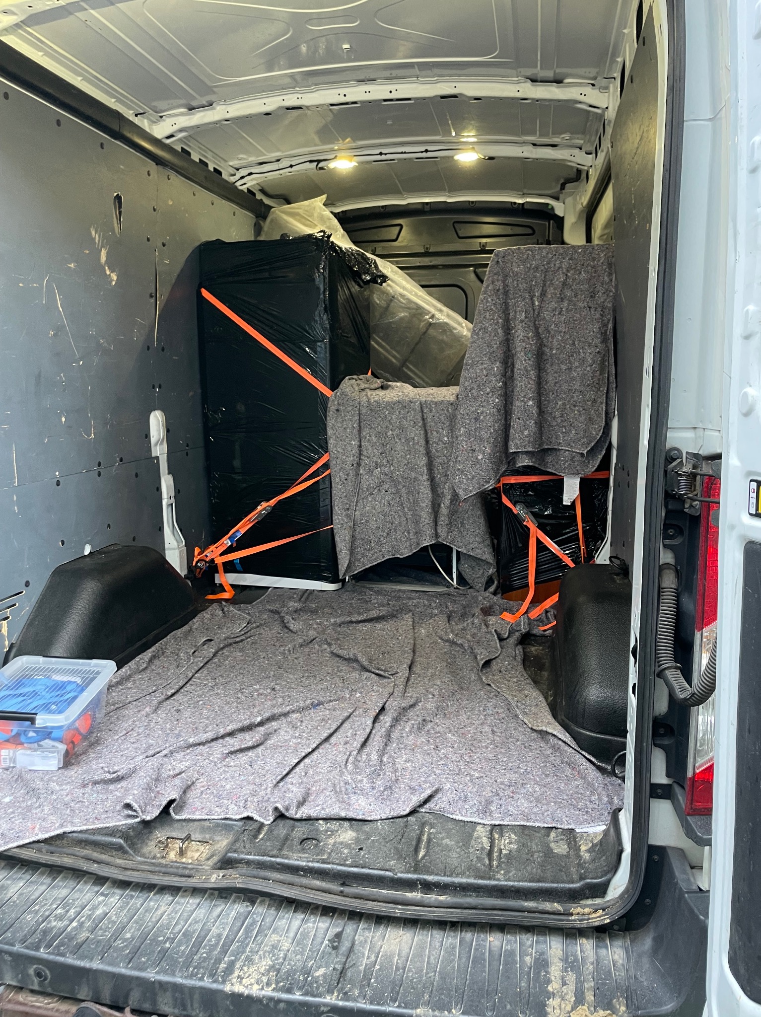 Wnętrze busa po załadunku: zabezpieczone meble folią i pasami, przykryte kocami transportowymi, gotowe do transportu. Widoczny boks z narzędziami.