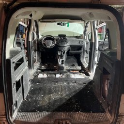 Lucky Detailing Polska OLEKSANDR SHCHUTSKYI - Wnętrze furgonetki przed czyszczeniem: widoczny kokpit, kierownica i pusta przestrzeń ładunkowa z zabrudzeniami na podłodze. Otwarta przestrzeń bagażowa.