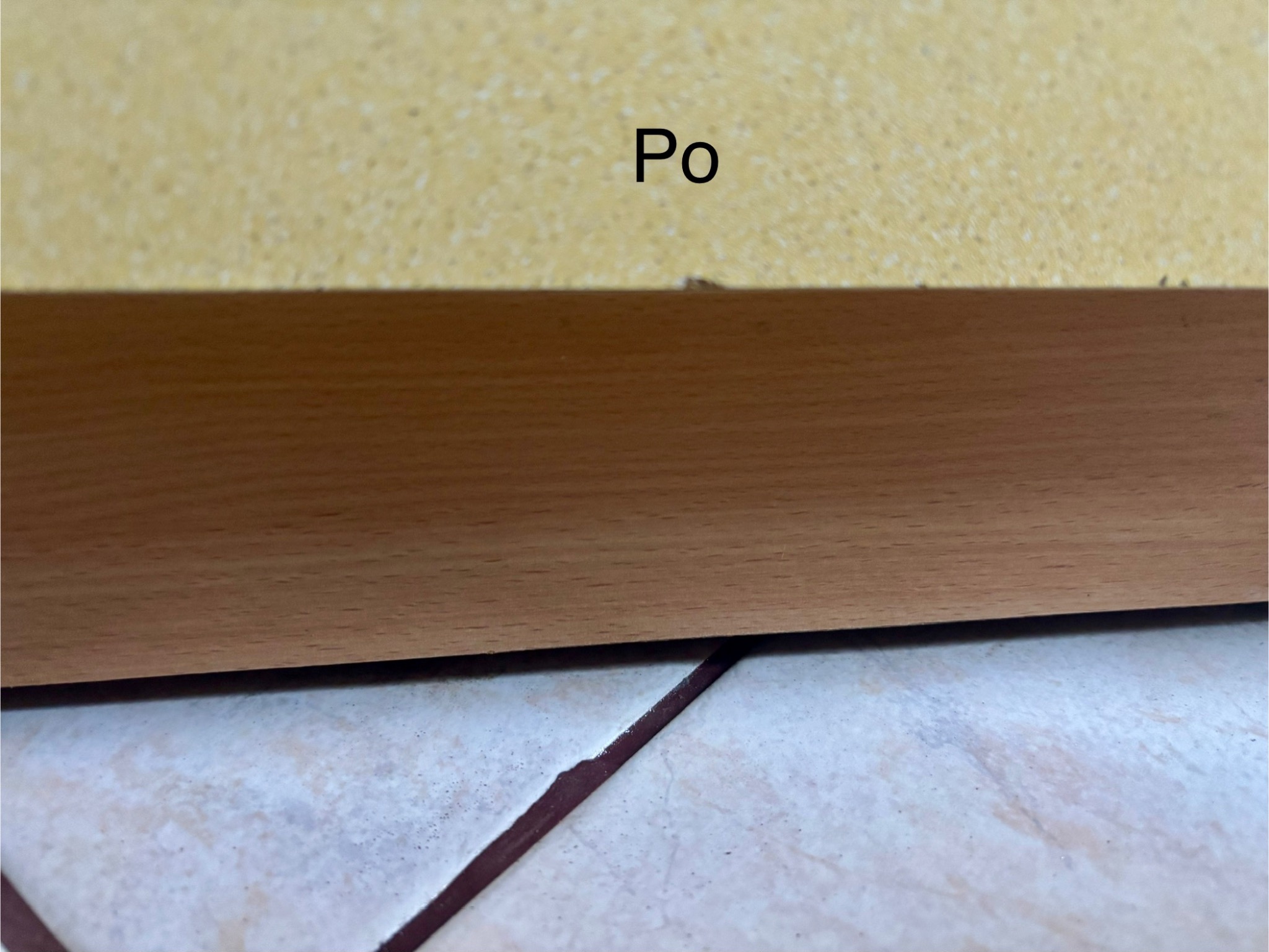 Fragment podłogi po sprzątaniu, widoczne płytki i listwa przypodłogowa. Napis 'Po' sugeruje efekt końcowy prac porządkowych.