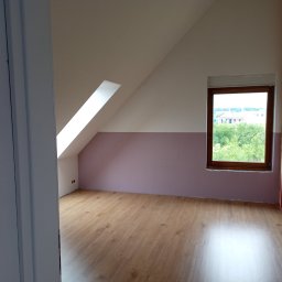 CraftPRO - Pokój na poddaszu po remoncie: drewniana podłoga, pomalowane ściany (fiolet i biel), okno z widokiem na zieleń, tęcza na ścianie. Widok zza uchylonych drzwi.