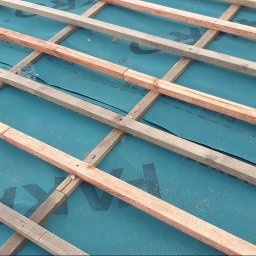 KedarInwest - Konstrukcja drewniana dachu z membraną hydroizolacyjną w kolorze turkusowym, tworząca siatkę. Widoczne elementy mocujące. Ujęcie z góry.