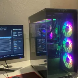 Komputer stacjonarny z podświetleniem RGB, widoczny monitor z parametrami sprzętowymi, mysz na podkładce. Sprzęt gotowy do pracy, konfiguracja po instalacji.