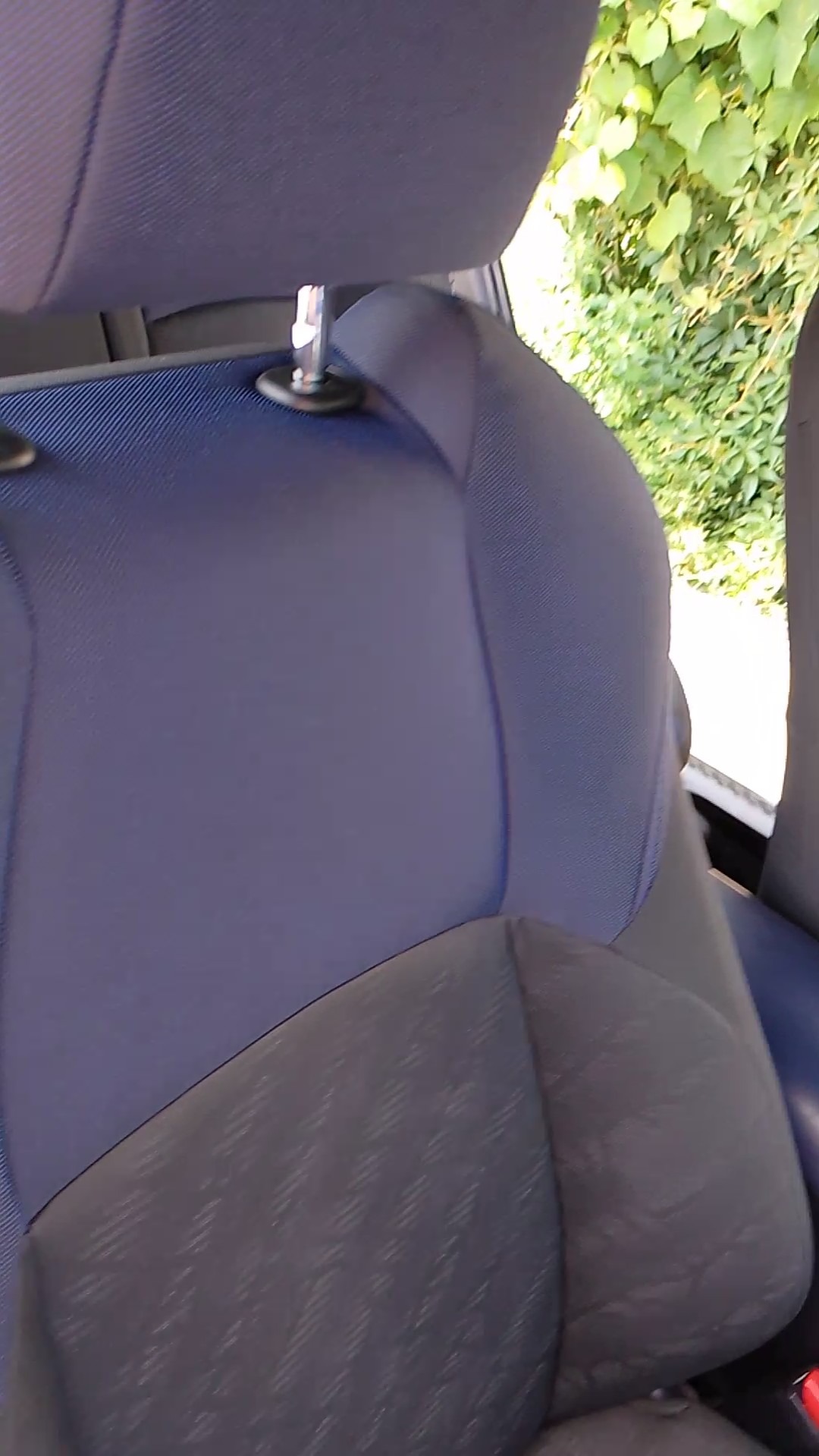 Tapicerka samochodowa w odcieniach niebieskiego i szarości, widoczna z bliska na fotelu w Kielcach, z zagłówkiem i fragmentem roślinności w tle.