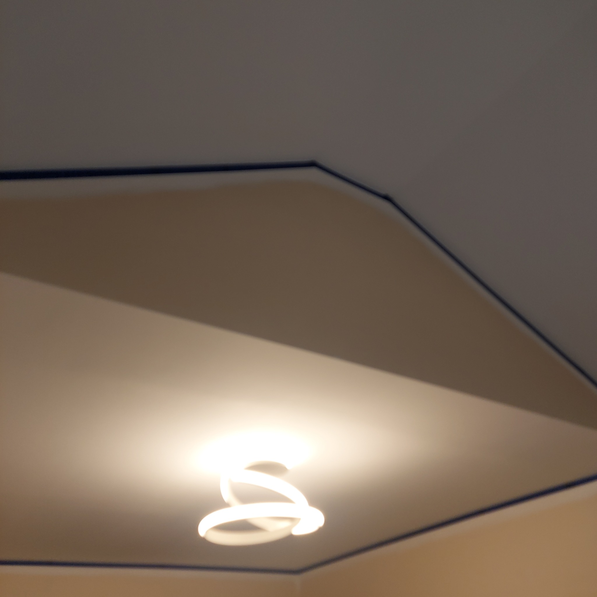 Wykończony sufit podwieszany z nowoczesnym oświetleniem LED. Widoczne precyzyjne łączenia i pomalowane listwy wykończeniowe. Neutralna kolorystyka ścian.