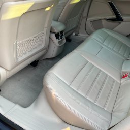 CarGlow Detailong - Jasne, skórzane tylne siedzenia w samochodzie, z widoczną siatką w kieszeni fotela i elementami wentylacji. Ujęcie wnętrza pojazdu w neutralnej tonacji.