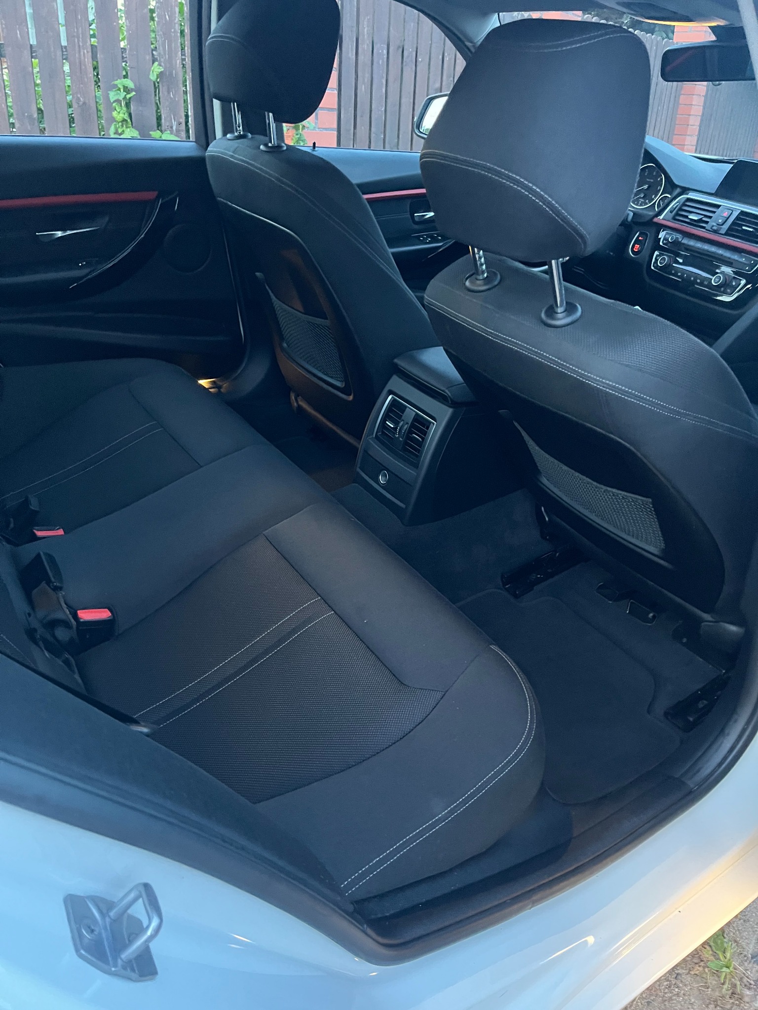 Wnętrze samochodu z czarną tapicerką, widok na tylne siedzenia i fragment deski rozdzielczej. Czyste, zadbane wnętrze auta.