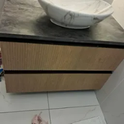 Nowoczesna łazienka: umywalka nablatowa w marmurowym wzorze, szafka z drewnopodobnym frontem i blatem imitującym kamień, czarna bateria.