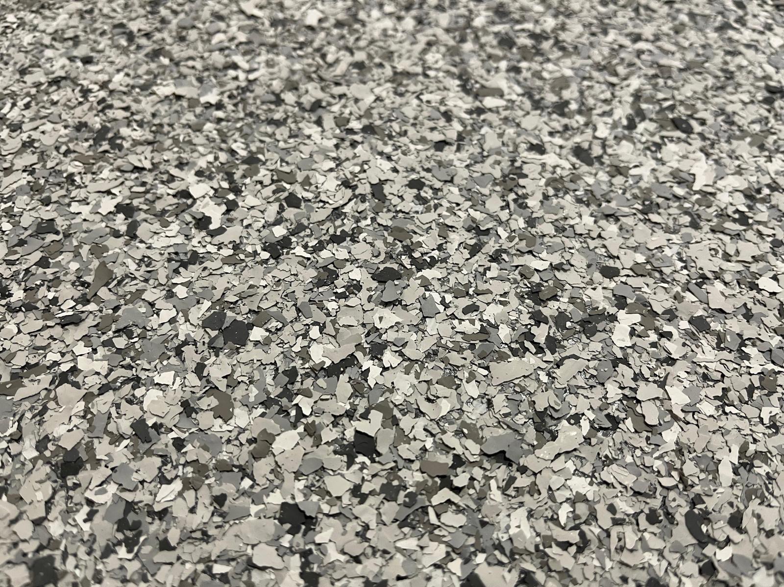Szara, dekoracyjna powierzchnia z drobnymi płatkami, tworząca jednolitą, nowoczesną teksturę. Idealna jako wykończenie podłogi w stylu industrialnym.