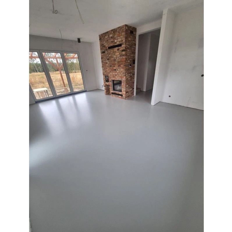 Jasnoszara, gładka podłoga w nowym wnętrzu z ceglanym kominkiem i dużym oknem balkonowym. Minimalistyczny design, połyskująca powierzchnia.