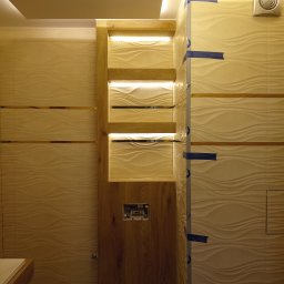 Mariusz haberman - Wykończona łazienka z podświetlanymi półkami z drewna i dekoracyjnymi płytkami w odcieniach beżu. Widoczny fragment umywalki.