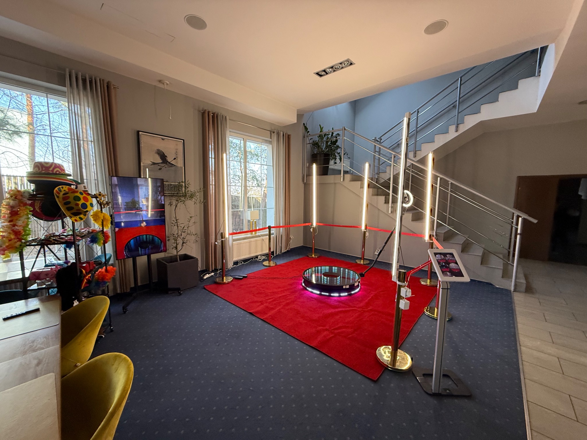 Rotacyjna fotobudka 360° z czerwonym dywanem, oświetleniem LED i rekwizytami w przestronnym wnętrzu, gotowa do użycia na imprezie.