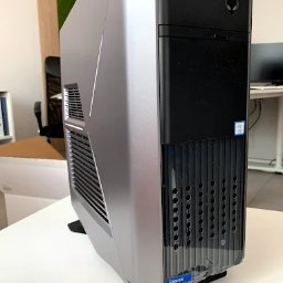 MKS Polska Rusinek Spółka Jawna - Stacjonarny komputer marki Alienware w srebrno-czarnej obudowie, stojący na biurku w jasnym pomieszczeniu biurowym. Widoczny z boku i przodu, z logo na obudowie.