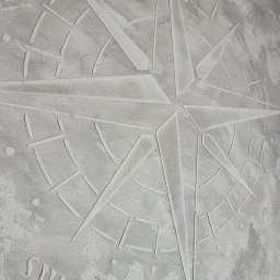 Wykończenia wnętrz - Dekoracyjna gładź na ścianie z motywem róży wiatrów, wykończona w odcieniach szarości. Efektowna tekstura i precyzyjne wykonanie detali.