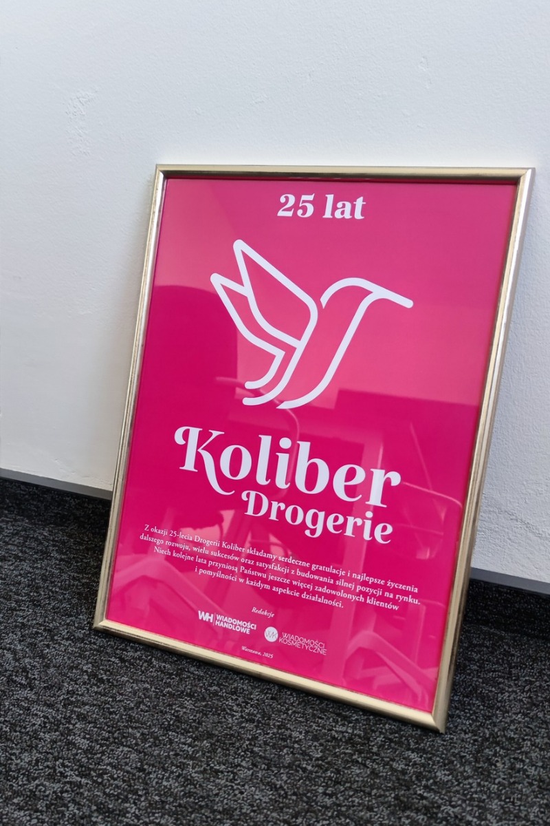 Oprawiony plakat z logo Koliber Drogerie na różowym tle, upamiętniający 25-lecie działalności, z tekstem gratulacyjnym i logotypami redakcji Wiadomości Handlowe i Kosmetyczne.