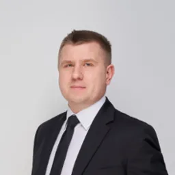 Portret mężczyzny w garniturze z krawatem na jasnym tle. Profesjonalny wizerunek prawnika lub doradcy.