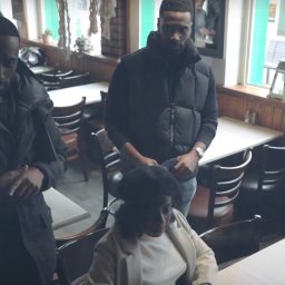 Urban Prism Media - Uczestnicy eventu w kawiarni, z widoczną tabliczką 'Reserved' na stole. Mężczyźni w kurtkach i kobieta w marynarce, uśmiechnięta, siedzą przy stolikach.