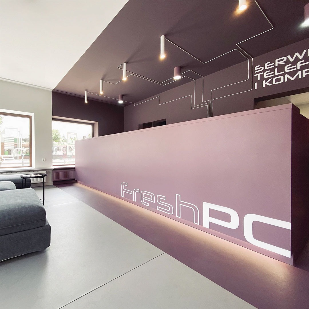 Nowoczesny salon serwisowy FreshPC z recepcją w odcieniach fioletu, białym logo, designerskim oświetleniem i napisem „Serwis telefonów i komputerów”.
