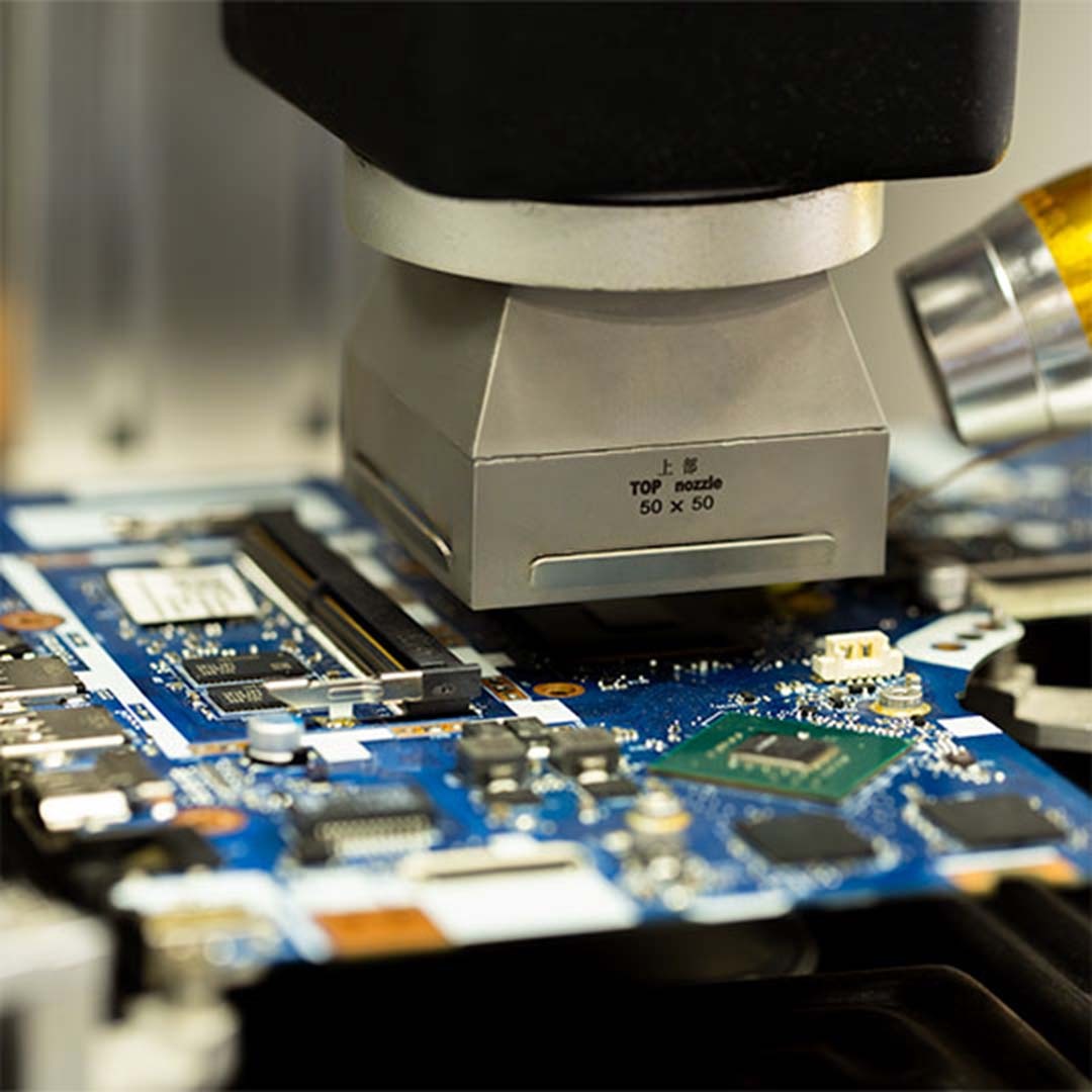 Detaliczne ujęcie płyty głównej laptopa poddawanej naprawie przy użyciu specjalistycznego sprzętu, z widoczną dyszą grzewczą TOP nozzle 50x50.