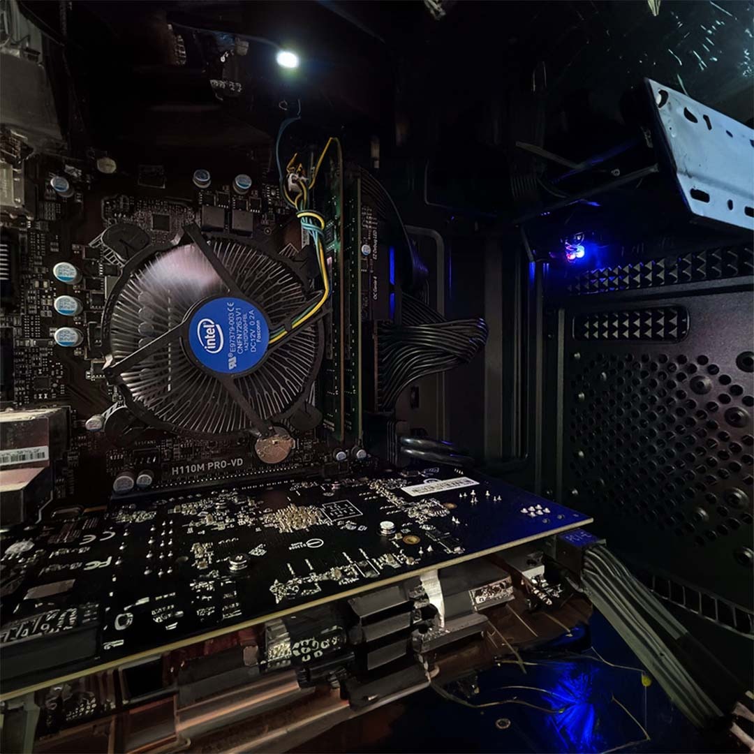 Wnętrze obudowy komputera stacjonarnego z płytą główną H110M PRO-VD, procesorem Intel i kartą graficzną. Widoczne elementy okablowania i oświetlenie LED.