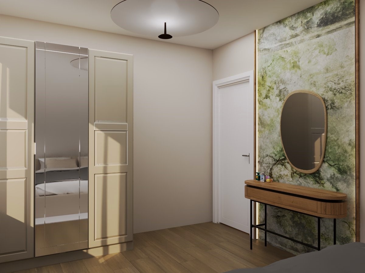 Kremowa szafa z lustrami odbija łóżko. Obok toaletka z owalnym lustrem na tle ściany w zielone wzory. Całość w jasnym, nowoczesnym wnętrzu.