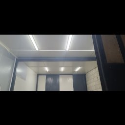 EL-KING - Wnętrze chłodni z panelami w biało-granatowe pasy i oświetleniem jarzeniowym, widziane z zewnątrz przez częściowo otwarte drzwi.