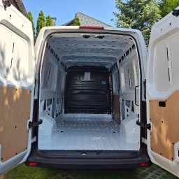 EURO TRANS GOLD SPÓŁKA Z OGRANICZONĄ ODPOWIEDZIALNOŚCIĄ - Wnętrze białego, pustego busa z otwartymi tylnymi drzwiami, gotowego do załadunku. Widoczna czysta podłoga i ściany, sugerujące przygotowanie do transportu.