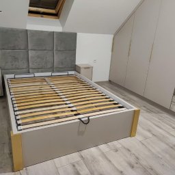 GraStol - Jasna sypialnia z łóżkiem z szarym wezgłowiem, szafkami nocnymi i szafą wnękową z lustrzanymi drzwiami. Widoczna drewniana podłoga i okno dachowe.