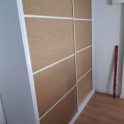 GraStol - Wnętrze z dużą, przesuwną szafą wnękową. Drzwi z paneli w odcieniach drewna, obramowane białymi listwami. Podłoga drewniana. Minimalistyczny design.