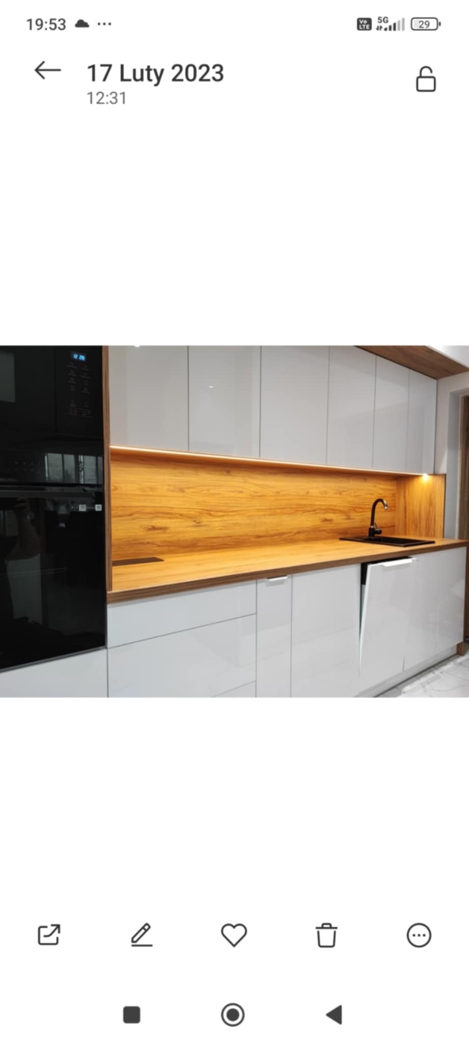 Nowoczesna kuchnia na wymiar: białe, lakierowane fronty, drewniany blat i panel, czarna armatura, oświetlenie LED podszafkowe.