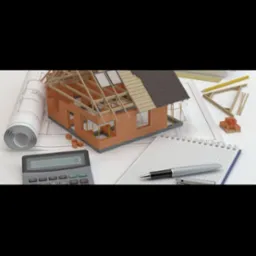Model domu w trakcie budowy z cegły, z widoczną konstrukcją dachu, leżący na planach architektonicznych z kalkulatorem i notatnikiem obok.